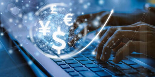 Imagen de manos escribiendo en el teclado con signos de yen, dólar y euro flotando arriba.