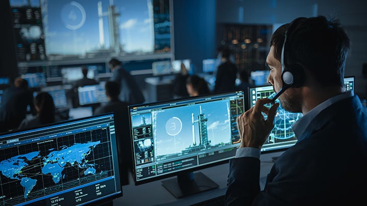 Man sits in missile launch control room during lift off working on embedded system