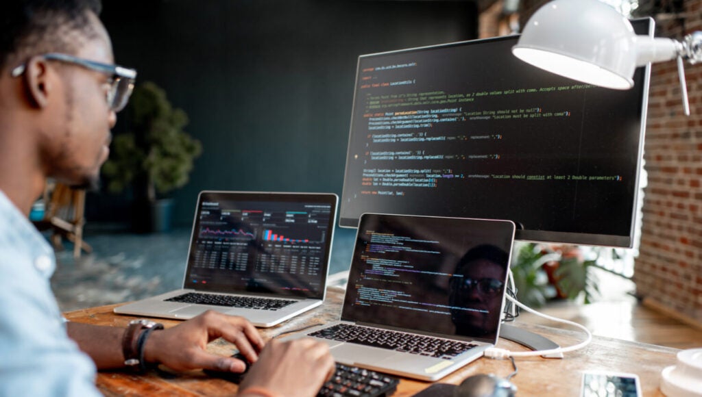Jeune développeur noir assurant la qualité et la fonctionnalité du code dans le processus de développement.