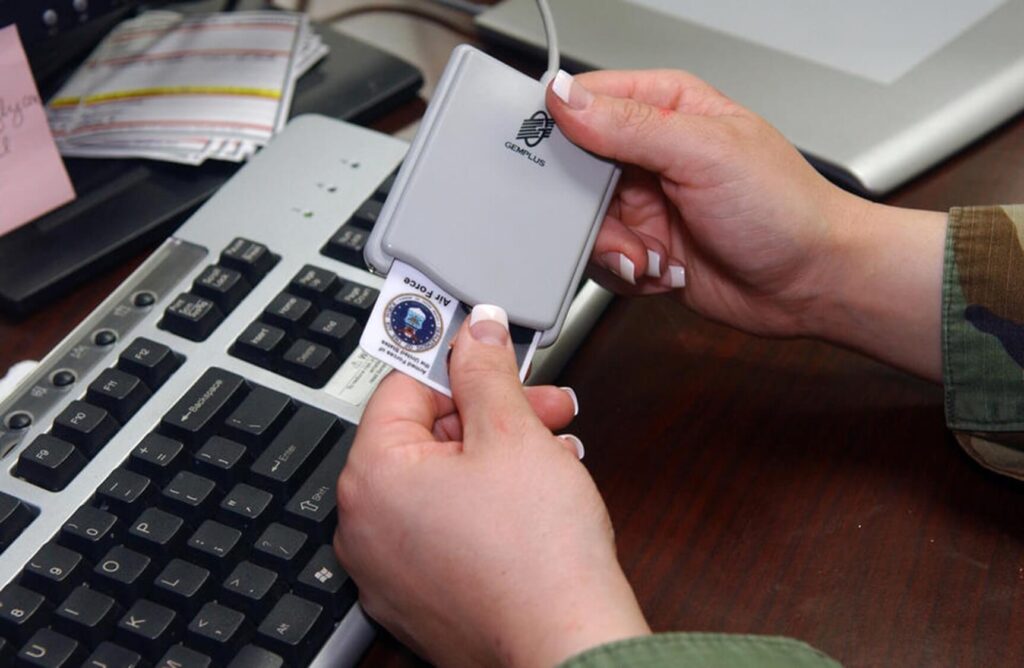 Photograph of someone inserting a PIV card into a card reader connected to a computer.