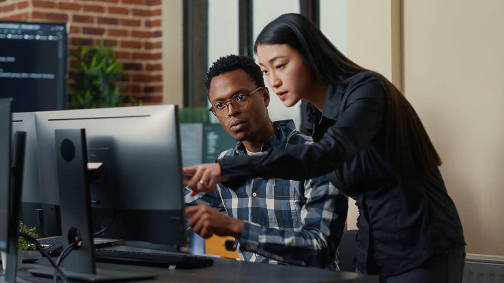 Image of two people at a computer screen working on TDM.