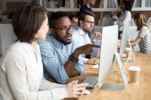 Imagen de jóvenes desarrolladores y probadores de software, hombres y mujeres, que colaboran y discuten los resultados de las pruebas