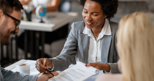 Image of a professional female banker dressed in a gray suit jacket going through a contract and smiling.