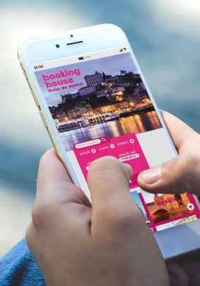 Close up image of a person with their fingers on a smart phone looking at a travel website